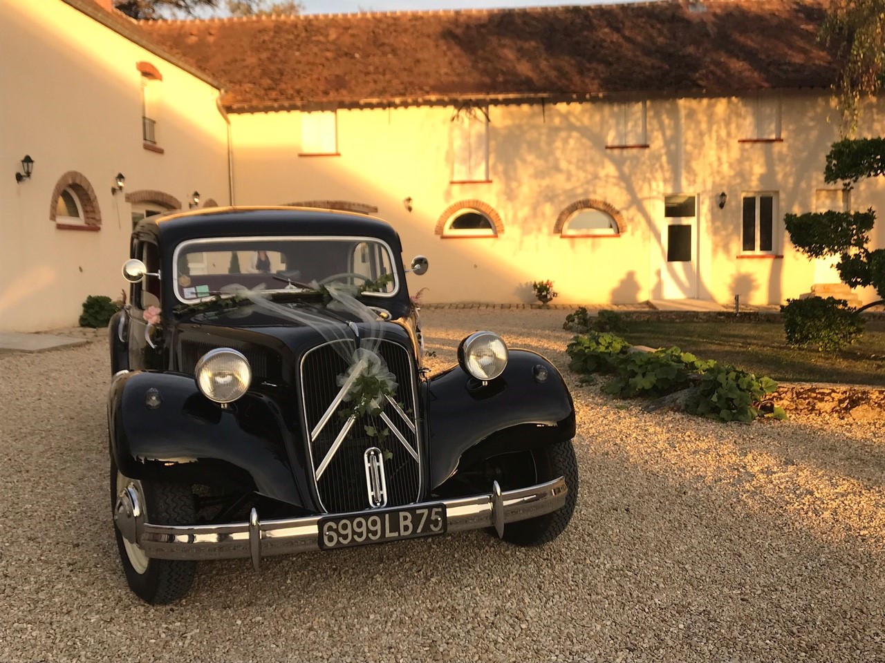 Voiture de mariage devant la ferme à la golden hour
