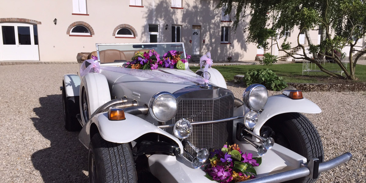 Voiture de mariage fleurie devant la ferme